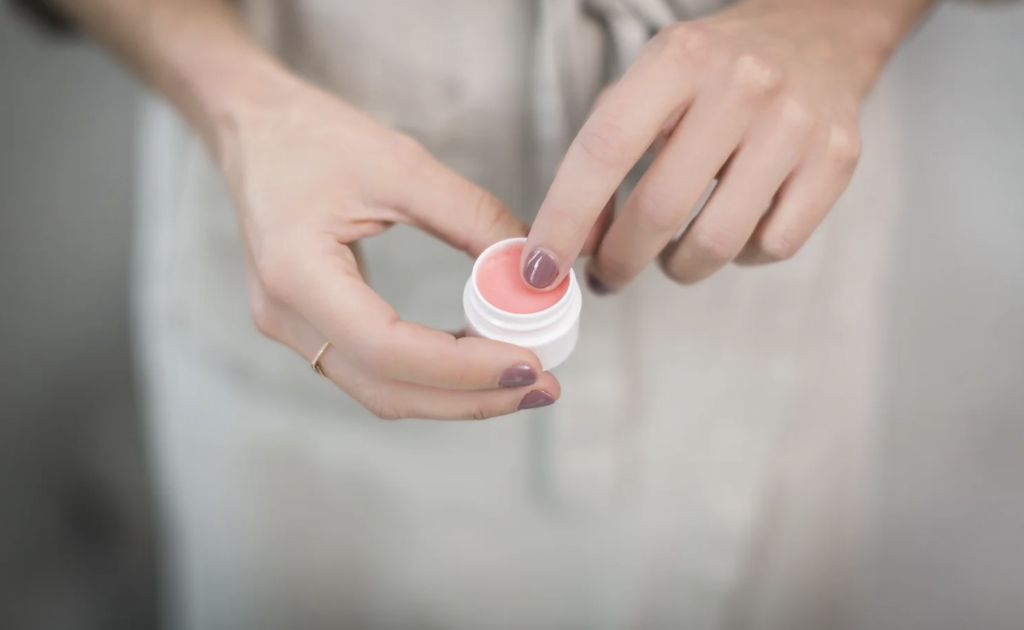 a woman holds a container of a pink wedding lip gloss